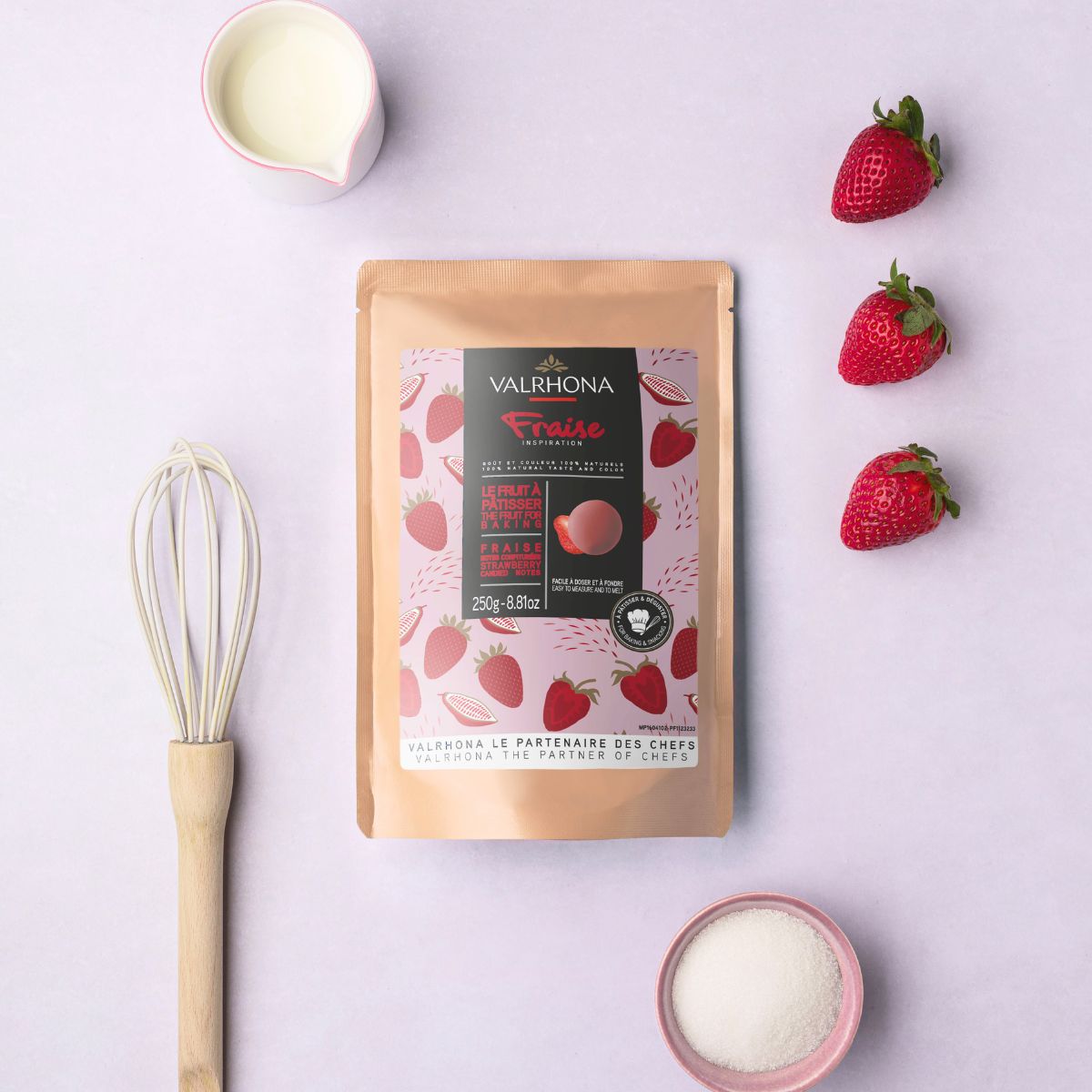 mise en ambiance du sachet inspiration fraise de valrhona avec des ustensiles de pâtisserie et des fraises fraiches