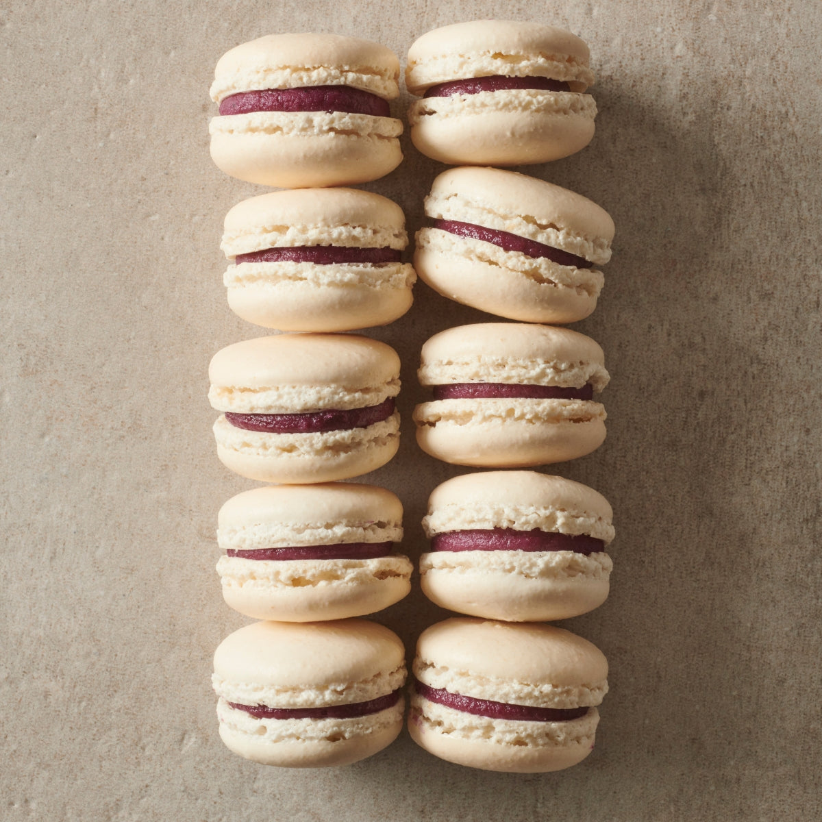 visuel de 10 macarons les uns à côté des autres avec de la purée de cassis dedans