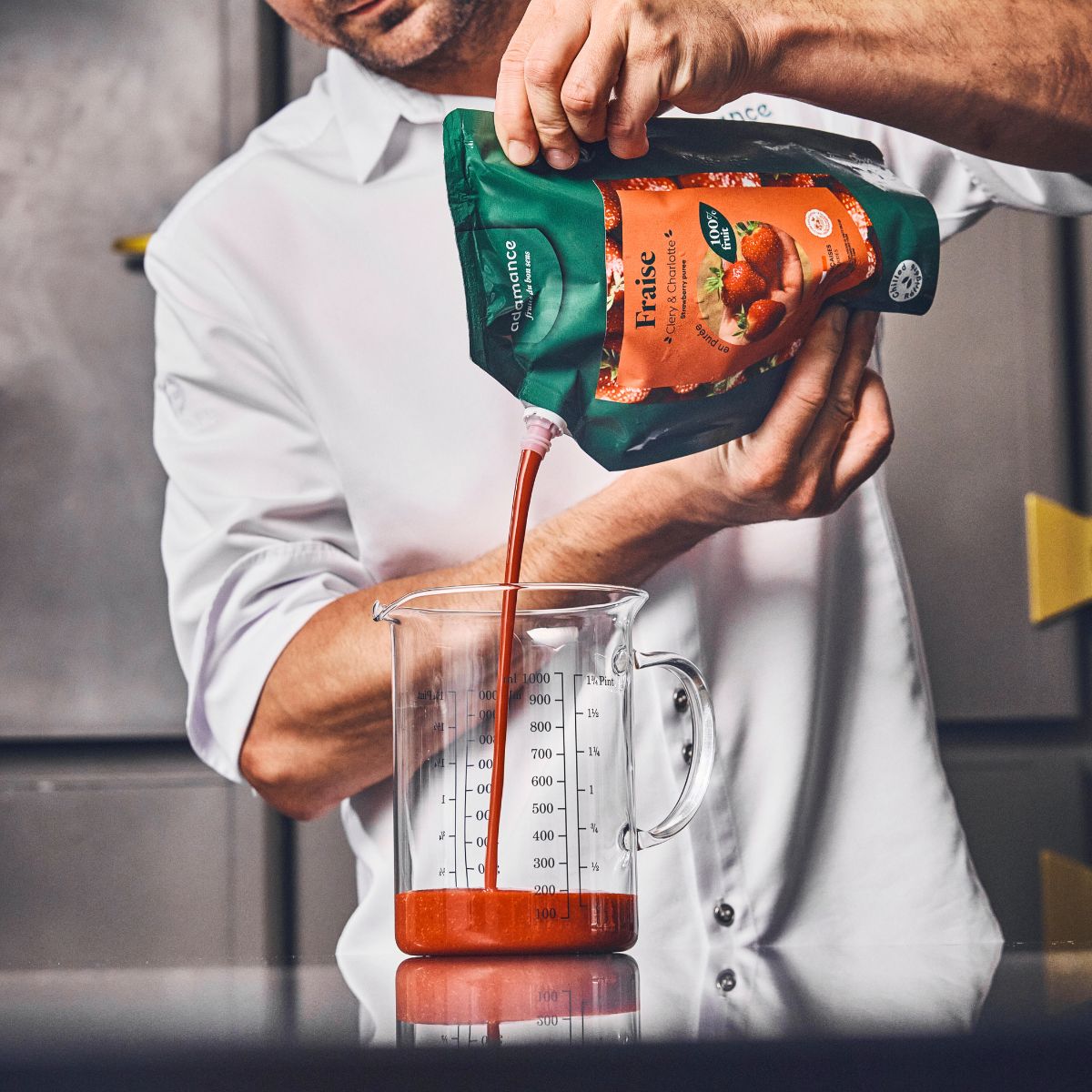 purée de fruit à la fraise en train d'être versée dans un verre doseur