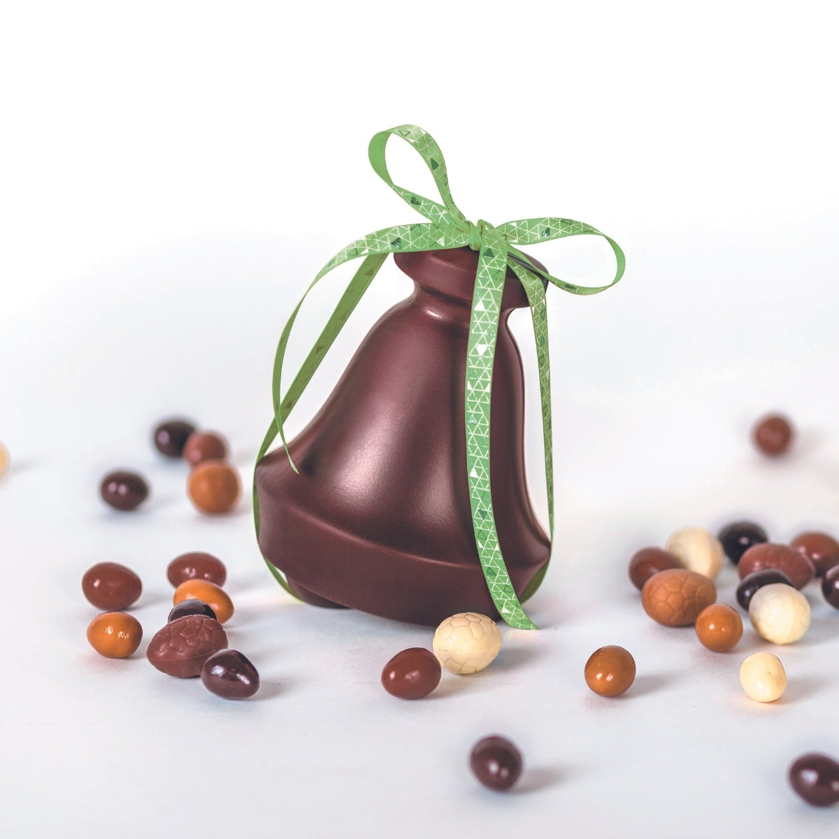 Cloche en chocolat noir avec petits oeufs de pâques à côté