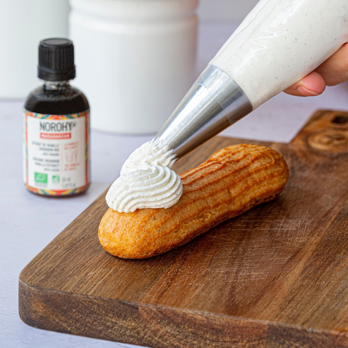 Personne en train de mettre de la crème à la vanille sur un éclair 