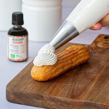 Personne en train de mettre de la crème à la vanille sur un éclair 